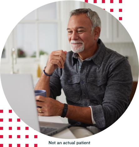 Older Man Sitting in Front of Computer With Beverage 